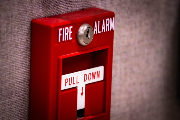 Manual fire alarm activation pull station on wall - signage read